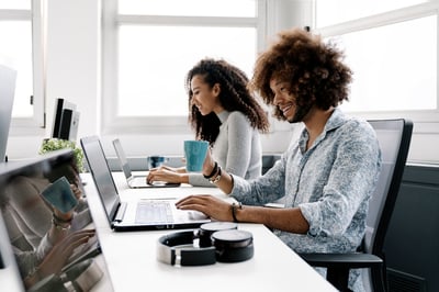 man and woman at computers in office